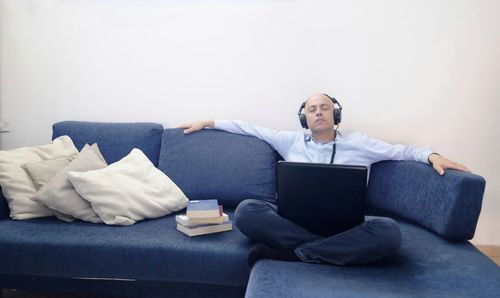 Businessman listening music while relaxing on sofa at office