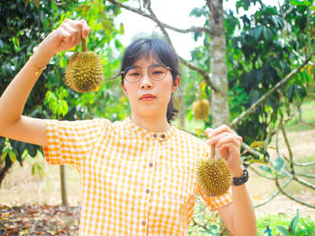 Portrait of smiling young woman showing fruit