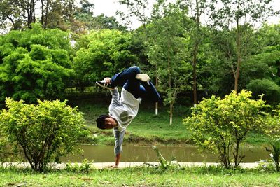 Man practicing stunt against trees in park