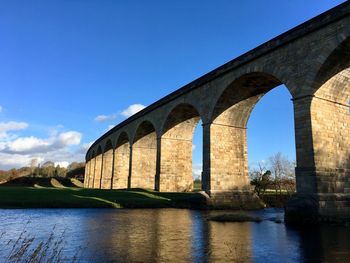 Low angle view of arch bridge over river against sky