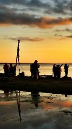 Silhouette people on beach against sky during sunset