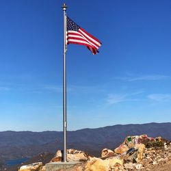 American flag on mountain against blue sky