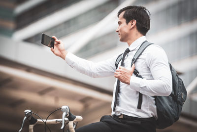 Man photographing with mobile phone in city