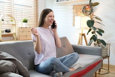 Young woman sitting on sofa at home