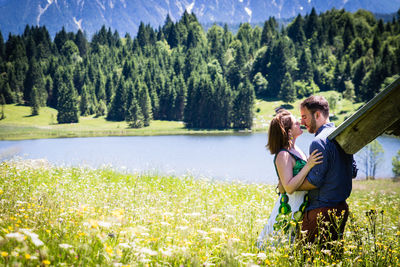 Side view of couple romancing while standing on grassy land