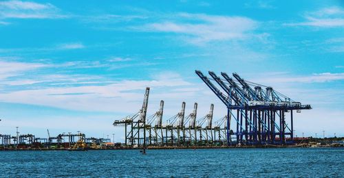 Cranes at commercial dock against sky