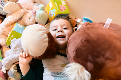 Cute young boy playing among a mountain of soft plush toys