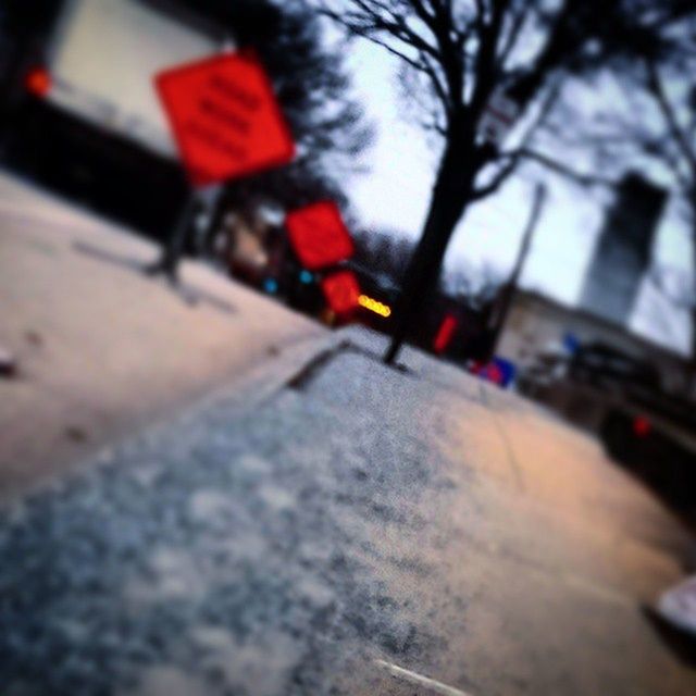 transportation, land vehicle, street, mode of transport, car, road, selective focus, focus on foreground, red, tree, day, building exterior, incidental people, city, bare tree, built structure, road marking, architecture, stationary, bicycle