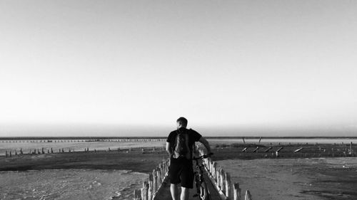 Rear view of man looking at sea against clear sky