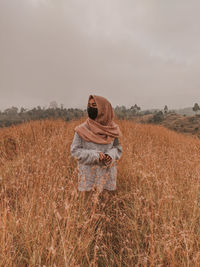 Woman standing on field against sky