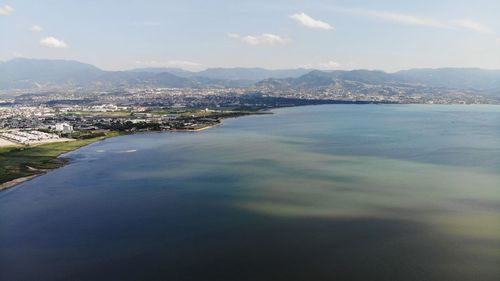 Aerial view of city by sea against sky