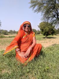 Man wearing sunglasses sitting on field