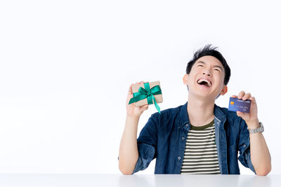 Portrait of smiling man holding camera over white background