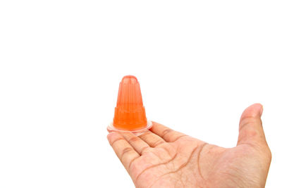 Close-up of hand holding orange against white background