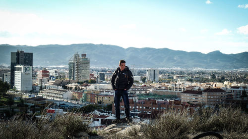 Man standing on city by buildings against sky