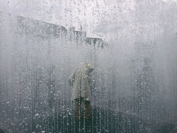 Person seen through glass window during monsoon