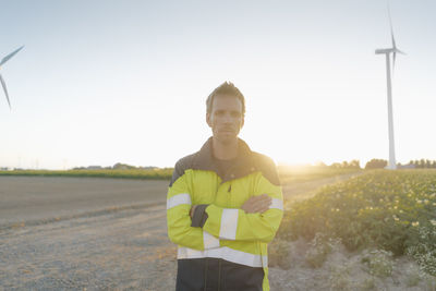 Portrait of engineer standing on field path at a wind farm