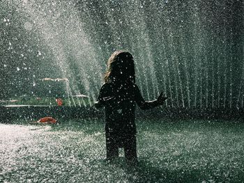 Silhouette girl standing in fountain