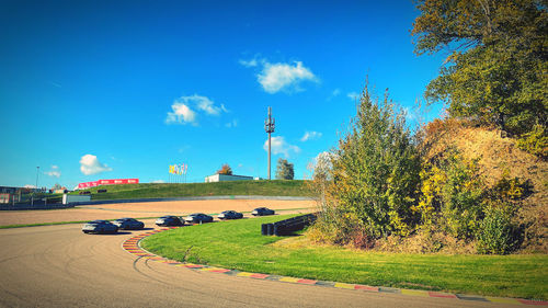 Road amidst trees and buildings against sky