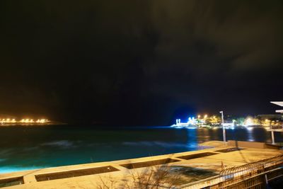 Illuminated sea against sky at night