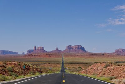 Road amidst landscape against clear blue sky