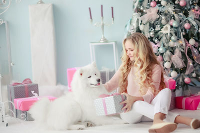 Portrait of woman with dog sitting on sofa at home