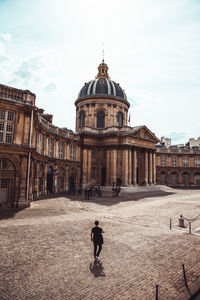 Rear view of man walking against building