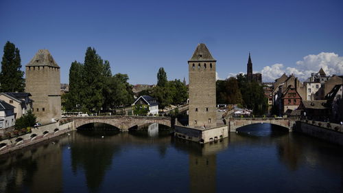 Arch bridge over river amidst buildings against sky