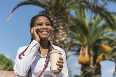 Portrait of young woman standing against trees