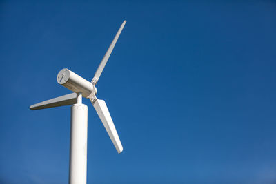 Low angle view of windmill against clear blue sky