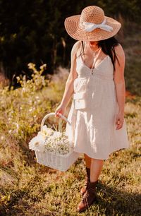 Midsection of woman holding hat in basket on field