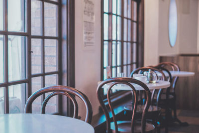 Empty chairs and table aside windows in coffee shop