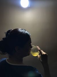 Woman drinking juice in darkroom