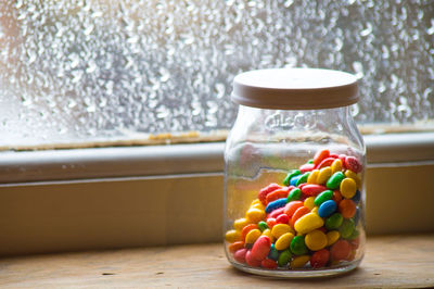 Close-up of multi colored jar with candies on table