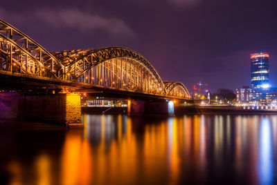 Illuminated bridge over river at night