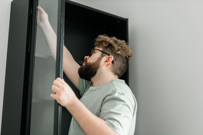 Side view of man looking through window