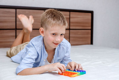 Portrait of boy playing on bed at home