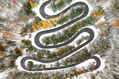 Aerial view of cars on winding road in winter forest