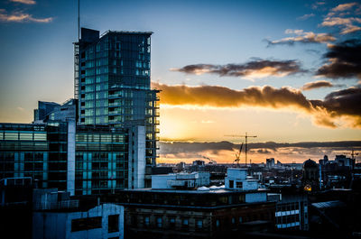 Buildings against cloudy sky at sunset