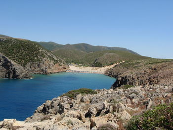 Scenic view of sea and mountains against clear blue sky