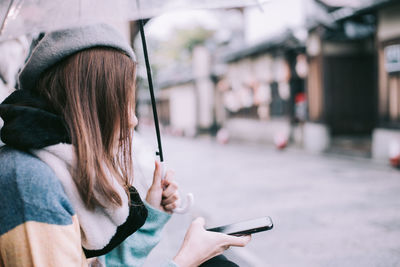 Woman using mobile phone on street in city