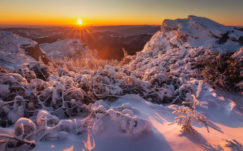 Scenic view of snowcapped mountains against sky during sunset in ceahlau mountains 