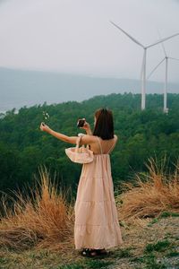 Rear view of woman standing on field against sky