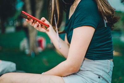 Midsection of woman holding mobile phone