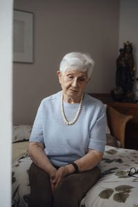 Worried senior woman sitting on bed at home