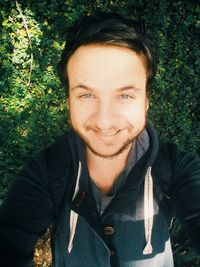 High angle portrait of man taking selfie while smiling against plants