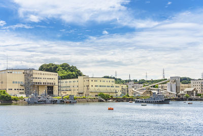 Buildings by river against sky in city