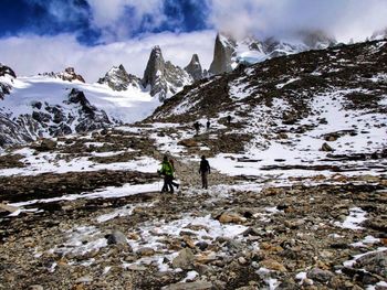 Rear view of person on snowcapped mountain against sky