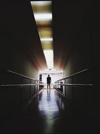 Silhouette people walking in illuminated tunnel