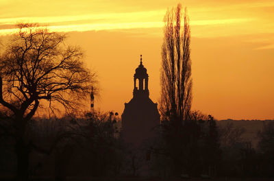 Silhouette trees and building against sky during sunset